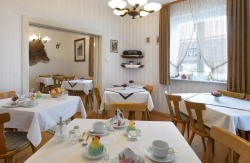 un restaurante con mesas y sillas con manteles blancos en Pension "Haus am Walde" Brodenbach, Mosel, en Brodenbach