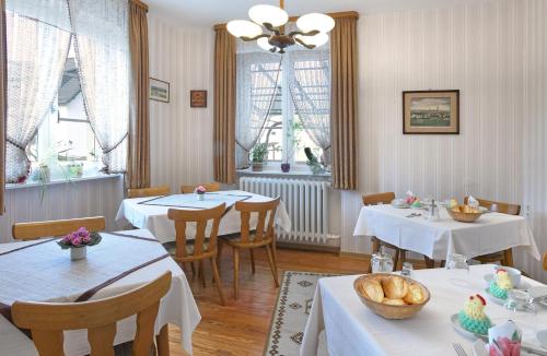 a restaurant with white tables and chairs and windows at Pension "Haus am Walde" Brodenbach, Mosel in Brodenbach