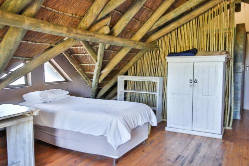 a bedroom with a white bed and a wooden ceiling at Oyster Bay Beach Lodge in Oyster Bay