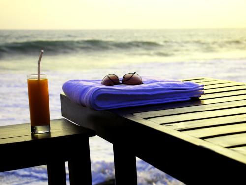 a pair of sunglasses and a drink sitting on a table at the beach at Randiya Beach Villa in Galle