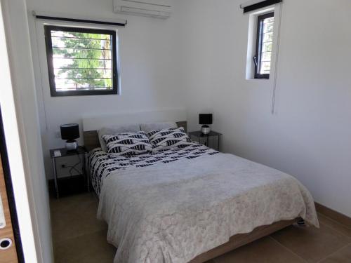 a white bedroom with a bed and two windows at Calanques Bandol ,T2 4 étoiles avec garage, dans pinède in Bandol