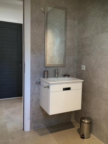 une salle de bain avec un lavabo blanc et un miroir dans l'établissement Villa Lucienne Bandol , T2 4 étoiles avec garage, dans les calanques, à Bandol