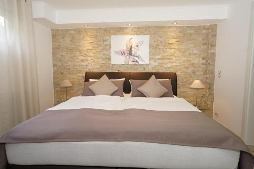 1 dormitorio con 1 cama grande y pared de ladrillo en York Cottage Garden, en Traben-Trarbach