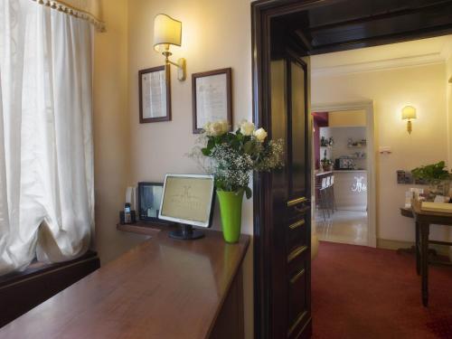 a room with a desk with a computer and flowers on it at Hotel Manganelli Palace in Catania