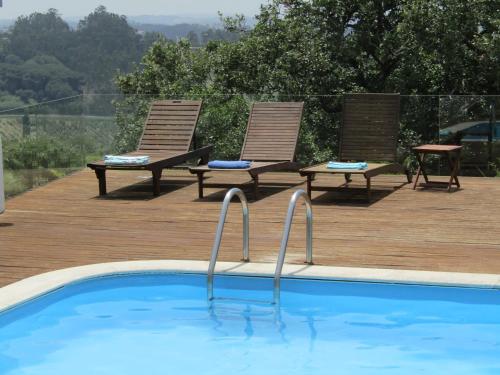 two chairs and a swimming pool on a wooden deck at Casal dos Melros in Cruzes