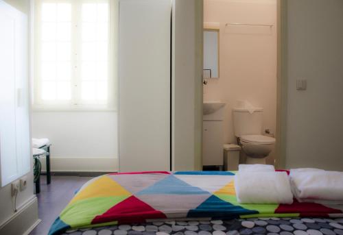 a bedroom with a colorful bed and a toilet at Alameda Guest House in Espinho