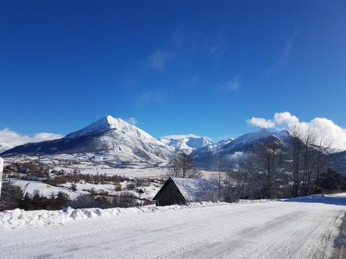 a snow covered road with a mountain in the background at Les Hauts Des Auches in Ancelle