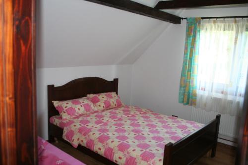 a bedroom with a bed with pink sheets and a window at Dobarlica in Dobîrlău