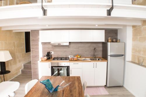 a kitchen with white cabinets and a wooden table at Sulla roccia dei Sassi in Matera