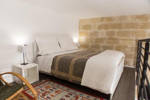 een slaapkamer met een bed en een bakstenen muur bij Sulla roccia dei Sassi in Matera