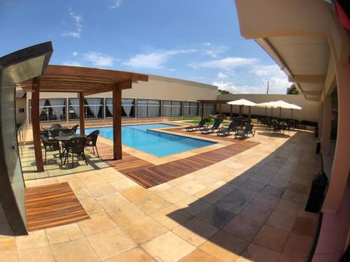 a patio with a pool and tables and chairs at Garoto Park Hotel in Floriano