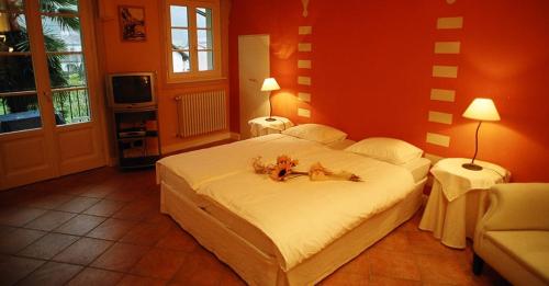 a bedroom with a large bed with two dogs on it at Hotel Casa Arizzoli in Cannobio