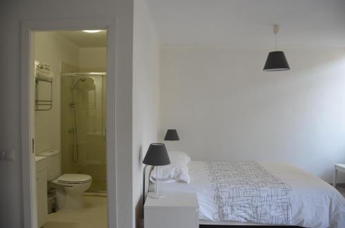 a white bedroom with a bed and a bathroom at Alameda Guest House RC in Espinho