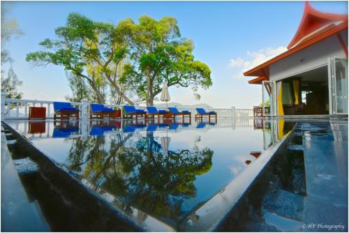 a swimming pool with blue chairs and a building at Villa REGTUK in Patong Beach