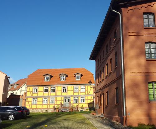 a yellow building with a red roof next to a street at Eldenhof in Plau am See