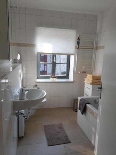 a white bathroom with a sink and a tub at Eldenhof in Plau am See
