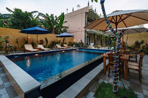 a swimming pool with tables and umbrellas next to it at Sari Nusa Inn in Nusa Lembongan