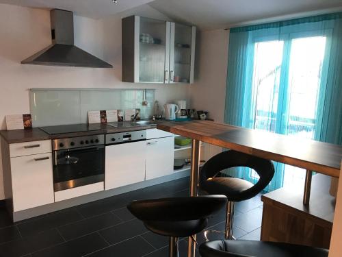 a kitchen with white cabinets and a counter with stools at Grosszügig und komfortabel:Ferienwohnung im Bayerischen Wald! in Wiesenfelden