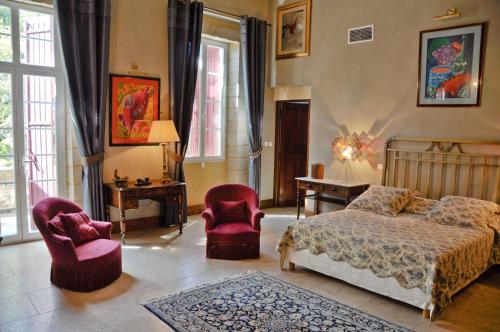 een slaapkamer met een bed en 2 stoelen bij Domaine du Grand Malherbes in Aimargues