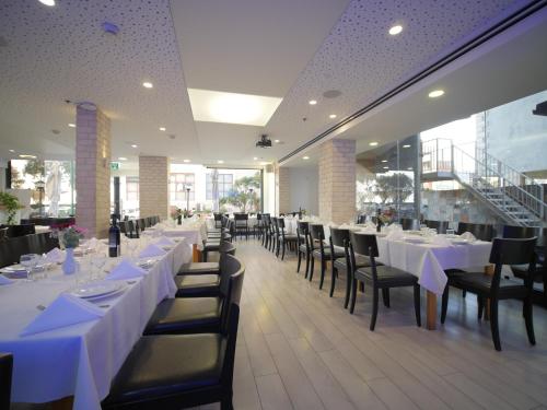 a dining room with white tables and black chairs at Margoa Hotel Netanya in Netanya