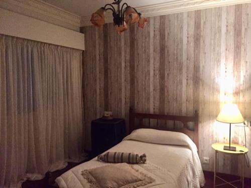 a bedroom with a bed and a lamp and curtains at Piso Bergantiños in Carballo