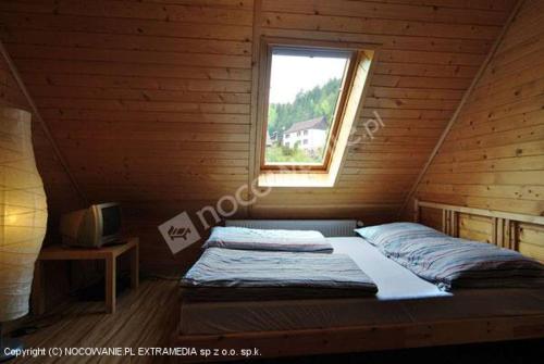 a bed in a wooden room with a window at Domek u Emilki in Korbielów