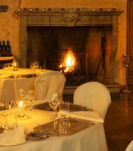 a table with white tables and chairs and a fireplace at Hotel Locanda Dei Mai Intees in Azzate