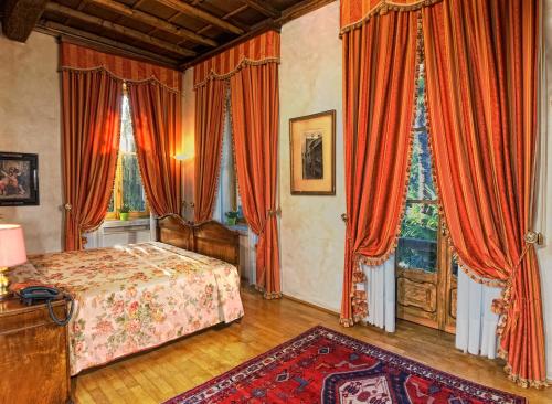 a bedroom with a bed with orange curtains and a rug at Hotel Locanda Dei Mai Intees in Azzate