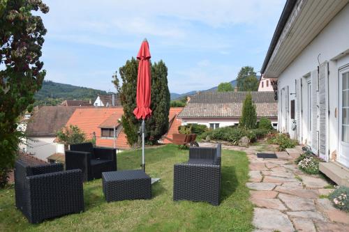 eine Terrasse mit Stühlen und einem roten Regenschirm in der Unterkunft Les Chambres du Beau Regard in Villé