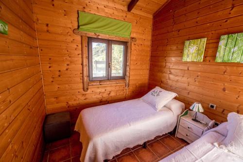 Dormitorio con cama y ventana en una cabaña de madera en Rural Tarifa Beach Las Cabañas, en Tarifa