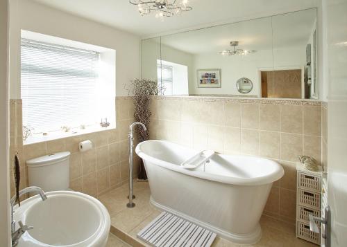 a bathroom with a tub and a toilet and a mirror at Host & Stay - View Point Apartment in Hinderwell