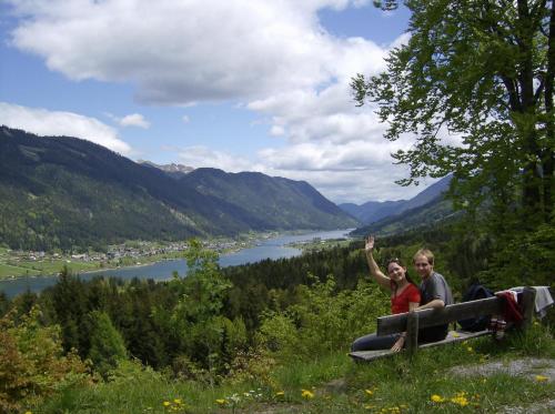 two people sitting on a bench overlooking a river at Haus Birke in Weissensee