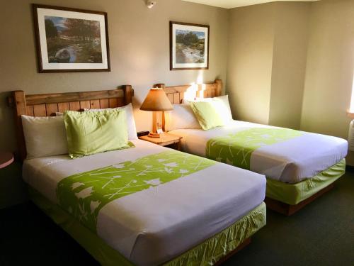 a hotel room with two beds with green sheets at Boulder Creek Inn in Donnelly