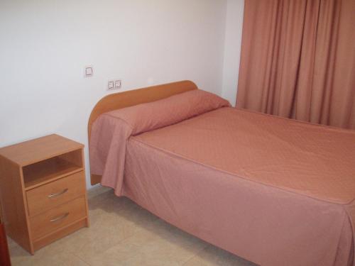 a small bedroom with a bed and a night stand at Apartahotel Los Hermanos in Ocaña