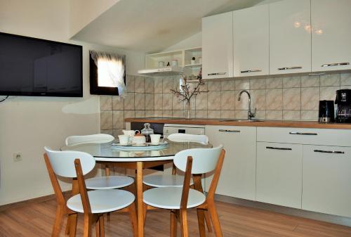 Una cocina con gabinetes blancos y una mesa y sillas. en Apartment Antonija, en Split