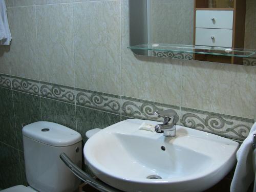 a bathroom with a sink and a toilet and a mirror at Apartahotel Los Hermanos in Ocaña