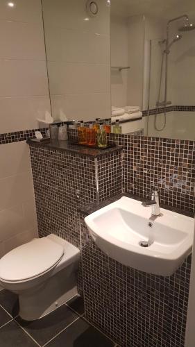 a bathroom with a white toilet and a sink at Stone House Hotel ‘A Bespoke Hotel’ in Stone