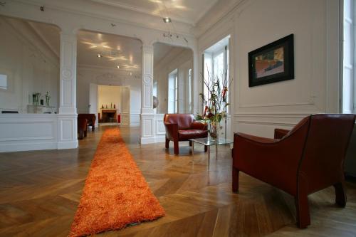 a living room with chairs and an orange rug at Chateau de Chassagne-Montrachet in Chassagne-Montrachet