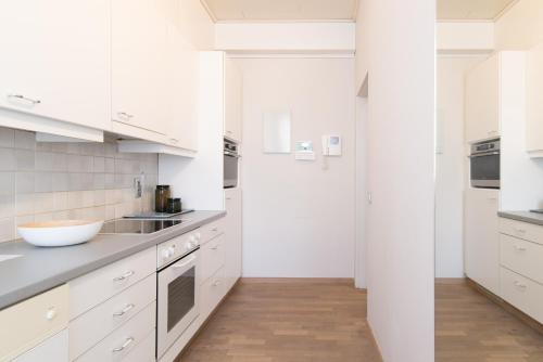 eine weiße Küche mit weißen Schränken und Holzböden in der Unterkunft App De Panne 1 in De Panne