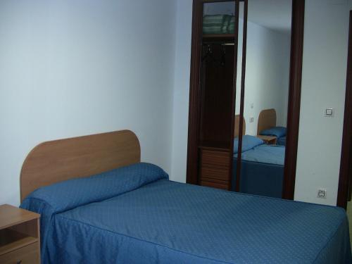 a bedroom with a blue bed and a mirror at Apartahotel Los Hermanos in Ocaña