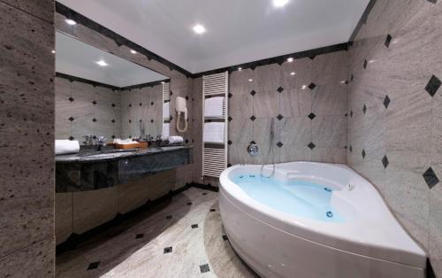 a large bathroom with a tub and a sink at Living Hotel Milano in Cornaredo