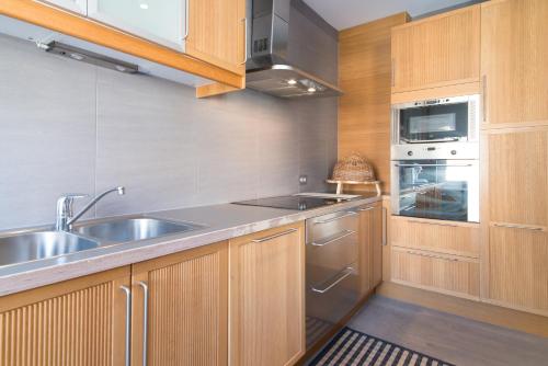 a kitchen with wooden cabinets and a stainless steel sink at App De Panne 2 in De Panne
