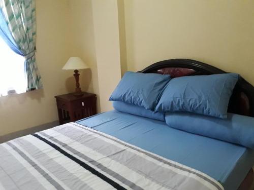 a bed with blue pillows on it in a bedroom at Lippo Carita Beach Utara Condo Noah in Carita