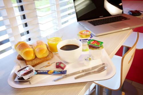 a tray of breakfast food on a table with a laptop at Premiere Classe Chelles in Chelles