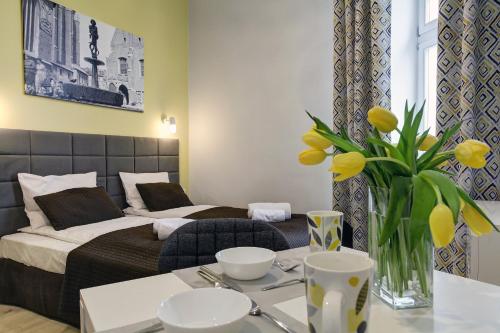 a hotel room with a bed and a table with yellow flowers at Grace Apartments in Krakow