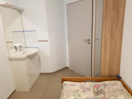 een kleine witte badkamer met een wastafel en een bed bij Hostel Gästehaus zum Padre in Goch