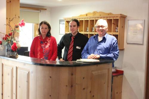 three people standing around a counter in a barber shop at Hotel Conrad in Scuol