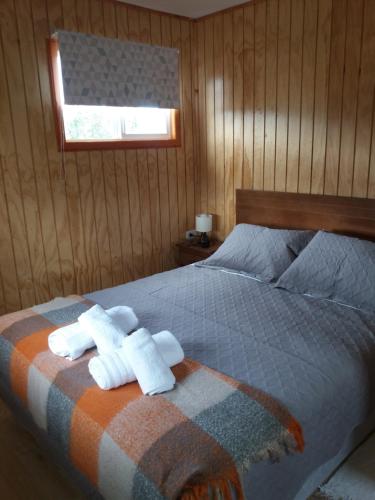 a bedroom with two towels on a bed at Cabañas El Leñador in Coihaique