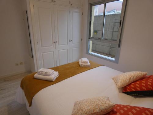 una camera da letto con un letto bianco e asciugamani di La Laguna, museo y parking a La Laguna