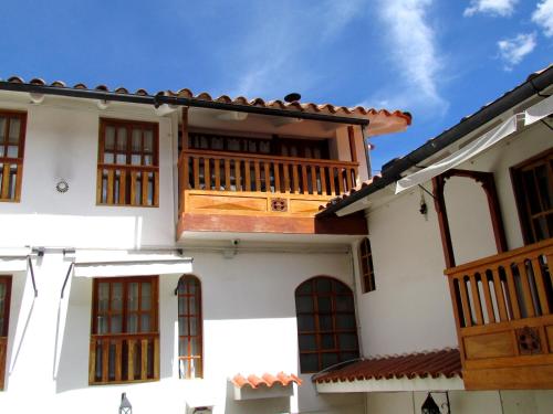 a white house with a wooden balcony at Quinua Boutique Apartments in Cusco